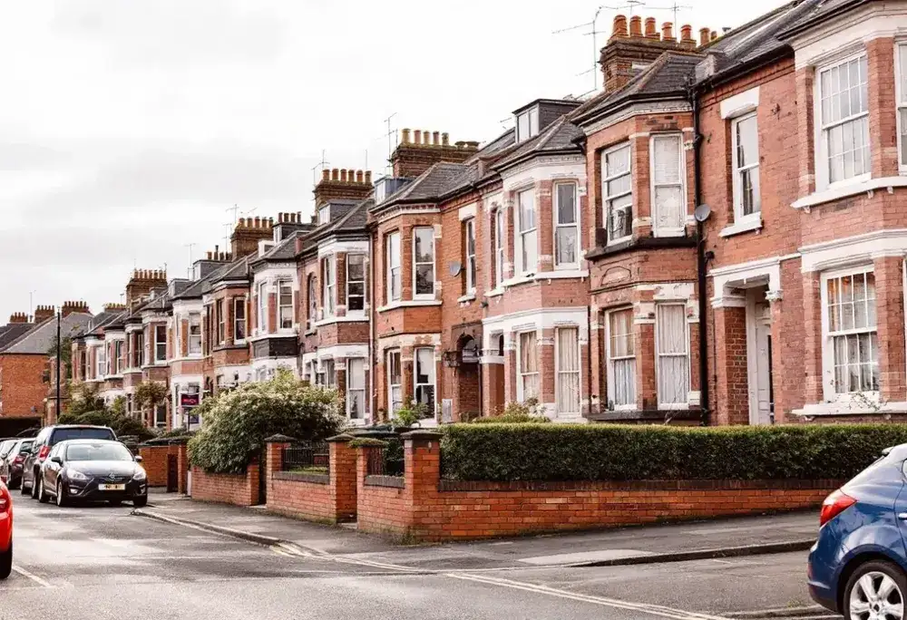 A row of Victorian red brick terraced houses with bay windows on a UK residential street
